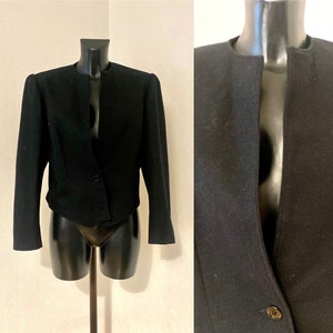 May include: A black cropped blazer with a single button fastening and a V-neckline. The blazer has long sleeves and a fitted silhouette.