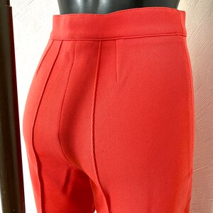 May include: A pair of coral red pants with a seam down the back of each leg.
