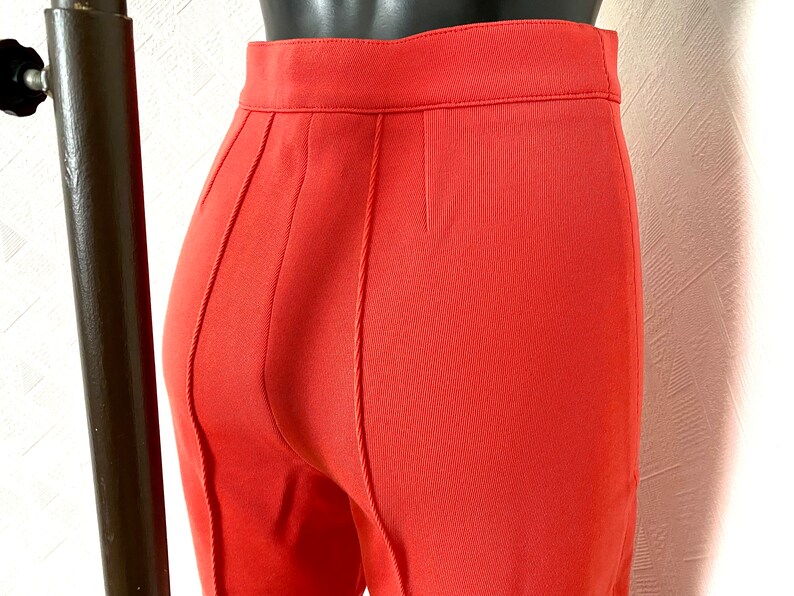 May include: A pair of coral red pants with a seam down the back of each leg.
