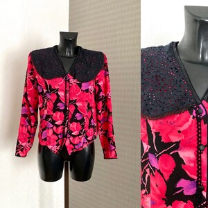 May include: A pink and black floral print blouse with a black lace collar and button front closure.