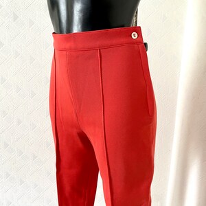 May include: A pair of red high-waisted pants with a button and zipper closure.