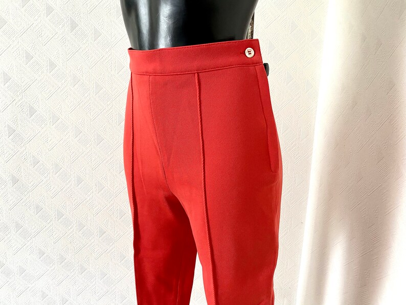 May include: A pair of red high-waisted pants with a button and zipper closure.