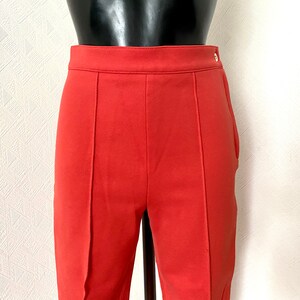 May include: A pair of red pants with a single button on the right side of the waistband.