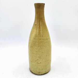May include: A light yellow ceramic vase with a textured surface. The vase has a narrow neck and a wide base.