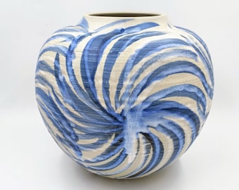 Può includere: Un vaso in ceramica bianca con un design a spirale blu e bianco. Il vaso è rotondo e ha un'ampia apertura.