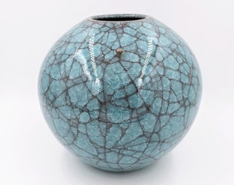 May include: A round, blue ceramic vase with a crackled glaze. The vase has a dark blue and brown crackle pattern.