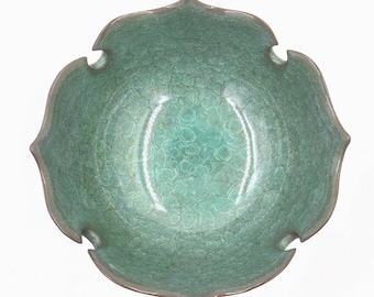 May include: A green ceramic bowl with a unique, textured glaze. The bowl has a five-pointed star shape and a slightly flared rim.