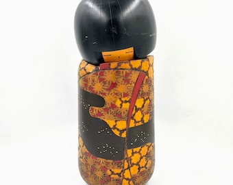 May include: A traditional Japanese wooden doll, known as a kokeshi, with a black hair and a colorful kimono with a floral pattern.