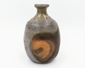 May include: A brown and gray ceramic vase with a textured surface and a swirl design. The vase has a narrow neck and a rounded body.