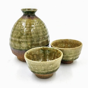 May include: A set of three ceramic sake ware in green and brown glaze. The set includes a bottle and two small cups.