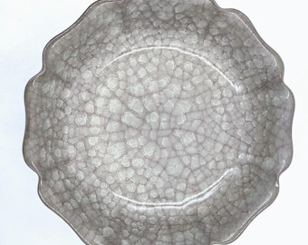 May include: A white ceramic bowl with a scalloped rim and a crackled glaze.