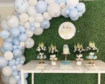 Könnte beinhalten: Ein weißer Tisch mit einem blauen und weißen Ballonbogen im Hintergrund. Der Tisch ist mit einem Kuchen, Cupcakes und anderen Leckereien dekoriert. Die Ballons sind kreisförmig angeordnet und buchstabieren "Baby"