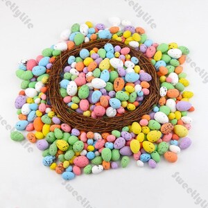 Puede incluir: Una gran colección de huevos de Pascua coloridos y moteados en un nido tejido. Los huevos son en tonos de rosa, azul, verde, amarillo y blanco.