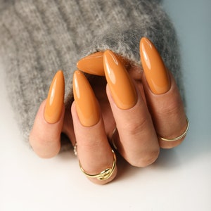 Orange press on nails for fall in warm pumpkin shade, long almond glossy nails