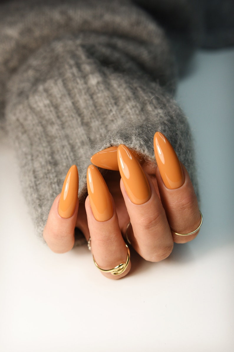 Orange press on nails for fall in warm pumpkin shade, long almond glossy nails