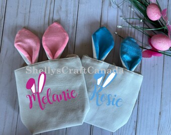 May include: Two personalized Easter bunny bags with bunny ears. One bag is pink and says "Melanie" and the other is blue and says "Rosie".