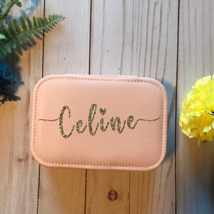 May include: A pink jewellery box with a gold glitter inscription that reads "Celine".