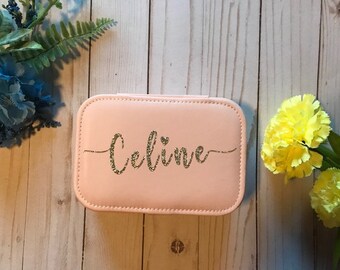 May include: A pink jewelry box with a gold glitter inscription that reads "Celine".