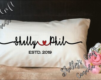 May include: White pillow with black cursive text that reads "Shelly ♥ Phil" and "ESTD. 2019".