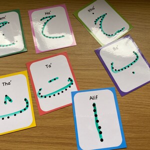 Peut inclure: Ensemble de huit cartes m&eacute;moire avec des lettres de l'alphabet arabe. Chaque carte pr&eacute;sente une lettre diff&eacute;rente avec des points et une ligne verte tra&ccedil;ant la lettre. Les cartes sont &eacute;tiquet&eacute;es avec le nom de la lettre en anglais.