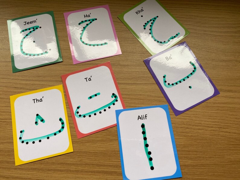 Peut inclure: Ensemble de huit cartes m&eacute;moire avec des lettres de l'alphabet arabe. Chaque carte pr&eacute;sente une lettre diff&eacute;rente avec des points et une ligne verte tra&ccedil;ant la lettre. Les cartes sont &eacute;tiquet&eacute;es avec le nom de la lettre en anglais.