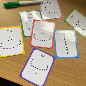 Peut inclure: Un ensemble de 8 cartes m&eacute;moire color&eacute;es avec des lettres de l'alphabet arabe &eacute;crites en anglais. Chaque carte a une couleur diff&eacute;rente et pr&eacute;sente une ligne pointill&eacute;e repr&eacute;sentant la forme de la lettre. Les lettres sont : Alif, Ba', Tha', Jeem, Ha', Ta', Kha'.