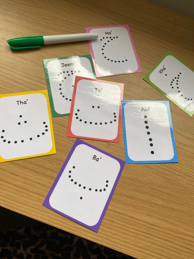 Peut inclure: Un ensemble de 8 cartes m&eacute;moire color&eacute;es avec des lettres de l'alphabet arabe &eacute;crites en anglais. Chaque carte a une couleur diff&eacute;rente et pr&eacute;sente une ligne pointill&eacute;e repr&eacute;sentant la forme de la lettre. Les lettres sont : Alif, Ba', Tha', Jeem, Ha', Ta', Kha'.
