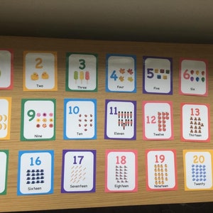May include: A set of 20 colorful flashcards with numbers 1 through 20, each featuring a different illustration and the number word. The cards are arranged in four rows of five cards each.