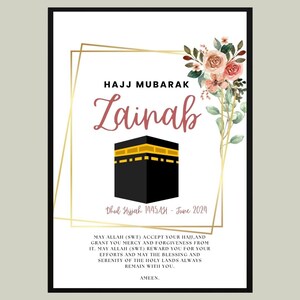 May include: A white card with a gold frame and floral accents. The card says "Hajj Mubarak Lainab" with the date "Dhul Hijah 1445AH - June 2024". The card also includes a black and gold image of the Kaaba.