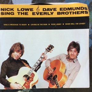 May include: A record album cover featuring Nick Lowe and Dave Edmunds, both holding acoustic guitars. The album title is "Nick Lowe & Dave Edmunds Sing The Everly Brothers". The album cover also lists the songs "Take A Message To Mary", "Crying In The Rain", "Poor Jenny", and "When Will I Be Loved?"