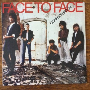 May include: A vintage record album cover with the title "FACE TO FACE" and the subtitle "CONFRONTATION". The cover features a band of five people standing in a dilapidated building. The band members are wearing casual clothing and have a serious expression on their faces.