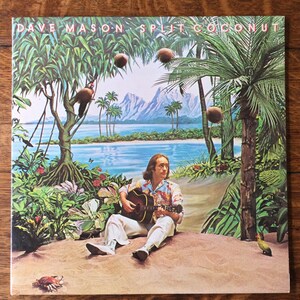 May include: A vintage album cover featuring a man playing a guitar on a tropical island. The album title is "Dave Mason Split Coconut".