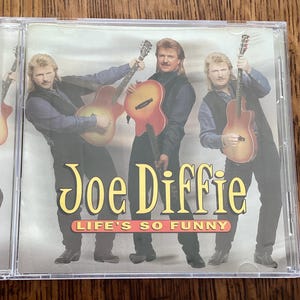 May include: A CD cover featuring a band called "Joe Diffie" with the album title "Life's So Funny". The cover features three men holding guitars, with a yellow background and black text.