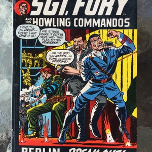 May include: A comic book cover featuring a red, white, and blue illustration of a soldier with a gun, and the text "Sgt. Fury and Howling Commandos" and "Berlin Break Out!"