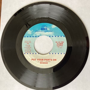 May include: Black vinyl record with a white label. The label has a blue and white logo that says "MSK Productions/Inc." and the song title "Put Your Pants On (K. Jones - J. Wilson) Winnie". The label also includes the song information: "MSK 789, 45 RPM, Stereo, Time: 3:37, 1979".