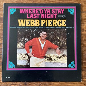 May include: Vintage vinyl record album cover for "Where'd Ya Stay Last Night" by Webb Pierce. The album cover features a photo of Webb Pierce in an orange sweater and cream pants. The album title and artist name are in bold text.