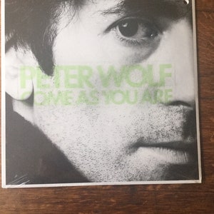 May include: Black and white photo of a man's face with the text "PETER WOLF COME AS YOU ARE" printed over the image.