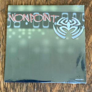 May include: A green CD case with the band name "NONPOINT" in red lettering and a white spider-like logo. The case has a barcode and the text "MCAR-25186-2".