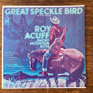 May include: Vintage vinyl record album cover for "Great Speckle Bird" by Roy Acuff and the Smoky Mountain Boys. The cover art features a cowboy riding a horse, holding a guitar, with text overlay. The album's tracklist is listed on the left side.