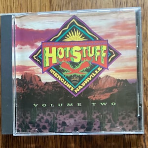 May include: A CD case with a colorful cover featuring the text "HOT STUFF" in green and yellow, with red chili peppers. The cover also includes the text "MERCURY NASHVILLE" and "VOLUME TWO" against a desert landscape.