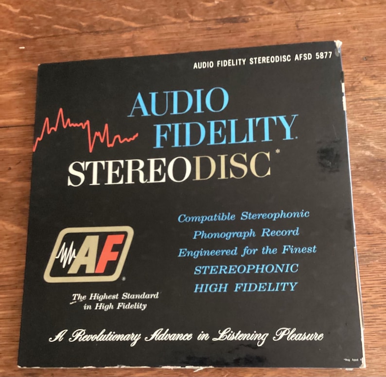 May include: A black Audio Fidelity Stereodisc record cover with white and blue text. The cover features the words "AUDIO FIDELITY STEREODISC" and the logo "AF". The text also includes "Compatible Stereophonic Phonograph Record".