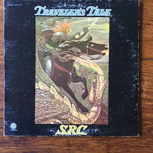 May include: A black vinyl record album cover with a colorful illustration of a knight riding a horse and fighting a dragon. The album title is "Traveler's Tale" and the artist is "SRC".
