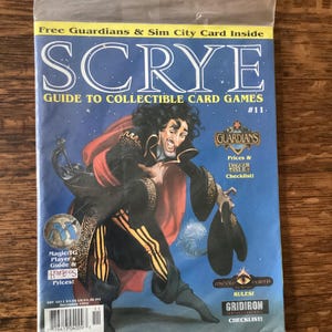 May include: A copy of SCRYE magazine, Guide to Collectible Card Games, issue #11, in a plastic sleeve. The cover features a fantasy illustration of a character in black and gold clothing. Includes "Guardians" and "Magic: The Gathering" content.
