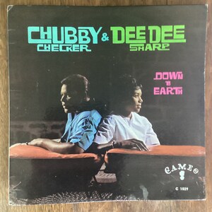 May include: A vintage vinyl record album cover featuring Chubby Checker and Dee Dee Sharp. The album title is "Down to Earth" and the record label is Cameo Records. The cover features a photo of the two artists sitting on a couch.