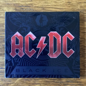 May include: A black CD case with a red and white AC/DC logo and the words "Black Ice" printed on the front.