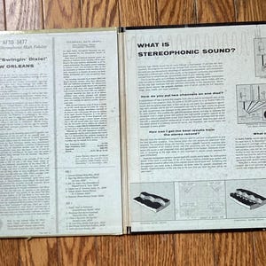 May include: An open vintage vinyl record album featuring the text "AL HIRT Swingin' Dial" and "AT DAN'S PIER 600 IN NEW ORLEANS". The album cover also includes text about stereophonic sound and diagrams.