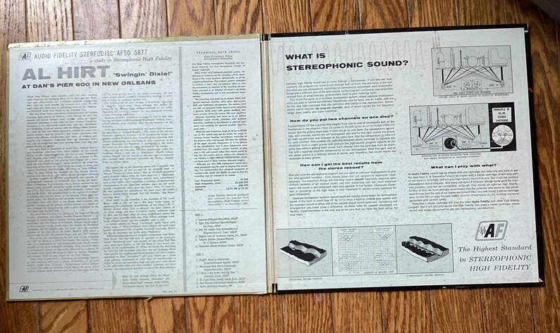 May include: An open vintage vinyl record album featuring the text "AL HIRT Swingin' Dial" and "AT DAN'S PIER 600 IN NEW ORLEANS". The album cover also includes text about stereophonic sound and diagrams.