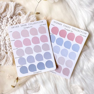 Può includere: Due fogli di adesivi con uno schema di colori pastello. Gli adesivi hanno la forma di lacrime e presentano diverse tonalità di rosa e blu. Il testo sui fogli recita "Dried Sage Collection" e "Oceans Coast Collection".