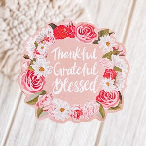 May include: Pink floral wreath sticker with the text "Thankful Grateful Blessed" in white cursive lettering.