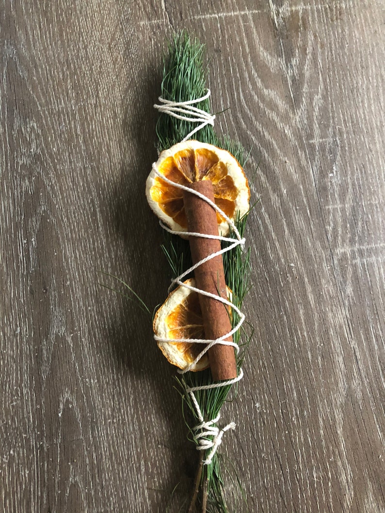 Peut inclure: Faisceau aromatique compos&eacute; d'une brindille de conif&egrave;re, d'un b&acirc;ton de cannelle et de deux tranches d'orange s&eacute;ch&eacute;es, le tout li&eacute; avec de la ficelle blanche. L'ensemble d&eacute;gage une esth&eacute;tique rustique et naturelle.